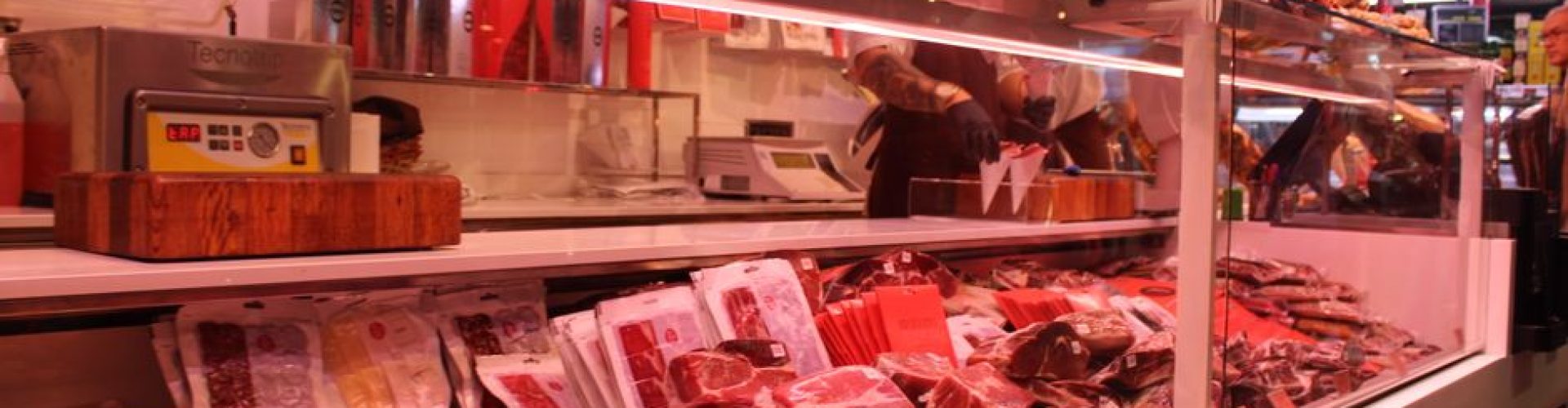 Fresh meat selection in a Barcelona market deli, vibrant display and diverse cuts.